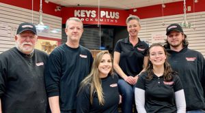 six people with black keys plus logo shirts standing inside a keys plus store