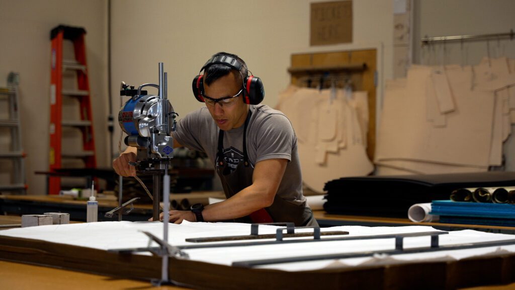A man wearing headphones and a gray shirt is working on a project.
